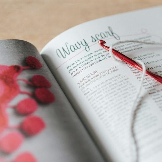 Crochet and thread on magazine in daytime